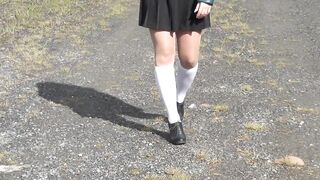 Schoolgirl in white knee socks and black shoes under the skirt